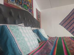 a bedroom with a bed with a black headboard and pillows at Titicaca Utama Lodge Perú in Puno