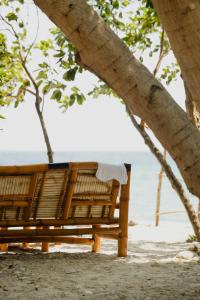 una panchina di legno sulla spiaggia sotto un albero di Amami Beach Resort a Puerto Galera