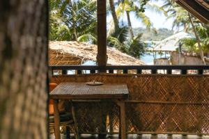 una mesa de madera en un balcón con vistas al océano en Amami Beach Resort, en Puerto Galera