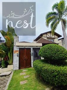 a house with a brown door and a palm tree at The Nest at Luana in Porac