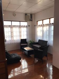 uma sala de estar com um sofá, cadeiras e janelas em บ้านสุขใจ (Ban Suk Jai) 