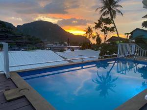 a swimming pool with a sunset in the background at Uphill Cottage in Phi Phi Islands