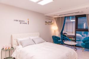 ein Schlafzimmer mit einem weißen Bett und blauen Stühlen in der Unterkunft Lotte Castle Marina in Yeosu