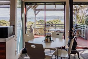 Una habitación con una mesa y sillas en un balcón. en Cool and Calm on Kiama, en St Helens