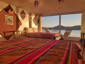 two beds in a room with a view of the water at Titicaca Utama Lodge Perú in Puno