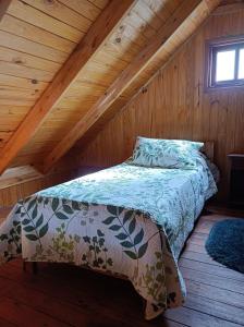 1 dormitorio con 1 cama en una cabaña de madera en Cabaña Aiken en Esquel