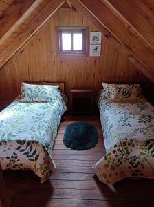 a attic room with two beds and a window at Cabaña Aiken in Esquel