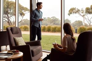 a man standing in front of a window talking to a woman at RACV Inverloch Resort in Inverloch