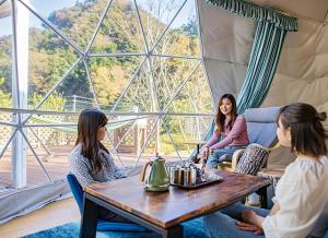 a group of women sitting around a table in a tent at Ufufu Village in Izu