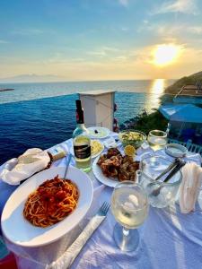 - une table avec des assiettes de pâtes et une bouteille de vin dans l'établissement Fabeno Villa, à Saranda