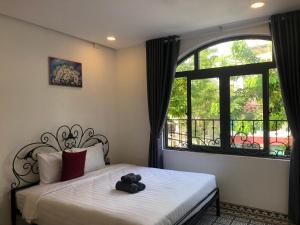 a teddy bear sitting on a bed in front of a window at TIMES HOTEL in Danang