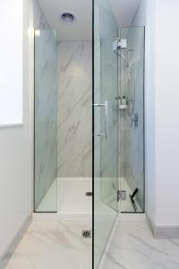 een douche met een glazen deur in de badkamer bij Central City Awaits 2 bed 2 bath with carpark in Christchurch