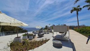 a patio with chairs and an umbrella and the ocean at Luxury 2 bedrooms Bolongo Punta Mita in Higuera Blanca