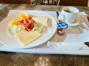 een wit bord met een broodje en een kopje koffie bij Mazaalai Hotel 