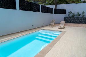 a swimming pool with two chairs next to a wall at Modern 3BR Home with Own Private Pool in Philipsburg