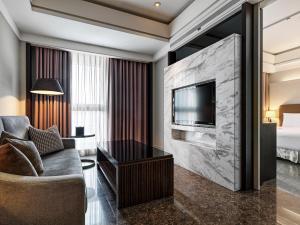 um quarto de hotel com um sofá, uma televisão e uma cama em Leofoo Residences em Taipei