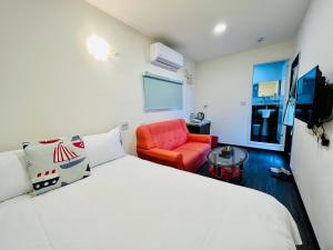 a bedroom with a white bed and a red chair at Tea King B&B in Yuchi