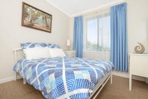 een slaapkamer met een bed met blauwe gordijnen en een raam bij Boomer - 4 Railway Tce, Port Elliot in Port Elliot