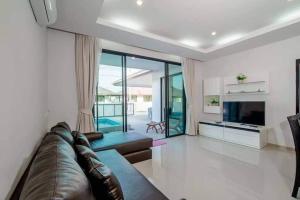 a living room with a leather couch and a television at E villa , private pool villa for your family in Hua Hin
