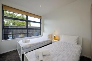 two beds in a room with a window at Whanau Retreat in Kaikoura