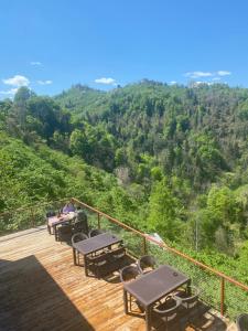 a deck with tables and chairs and a view of a mountain at Hobbitköy giresun in Giresun