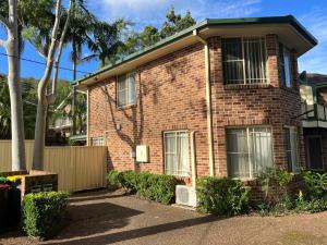 a red brick house with a fence and trees at 3 Bedroom Town house near Gosford CBD Sleeps 6 plus in Gosford