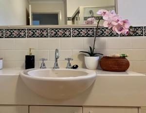 baño con lavabo blanco y flores en una encimera en 3 Bedroom Town house near Gosford CBD Sleeps 6 plus en Gosford