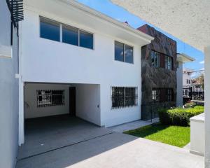 a white house with a garage next to a building at Casa full equipada en Centro Histórico in Cuenca