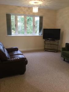 a living room with a couch and a flat screen tv at ChurstonBnB, private flat within family home, Bolton in Lostock