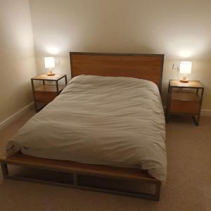 a bed with white sheets and two nightstands with lamps at ChurstonBnB, private flat within family home, Bolton in Lostock