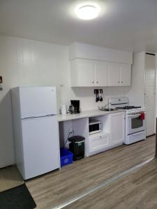 una cucina con elettrodomestici bianchi e armadietti bianchi di Midtown Motel on Alaska Ave a Dawson Creek