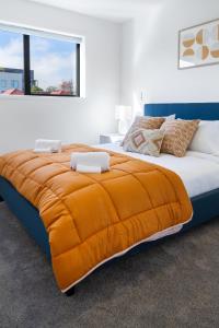 een slaapkamer met een groot bed en een oranje deken bij The City's Best Kept Secret 2 bed 2 bath in Christchurch