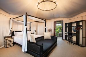 a bedroom with a black canopy bed and a chandelier at Natra Bintan, a Tribute Portfolio Resort in Lagoi
