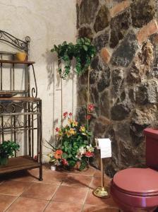La salle de bains est pourvue de fleurs, de toilettes et d'un mur en pierre. dans l'établissement Amankaya Atitlan, à Cerro de Oro