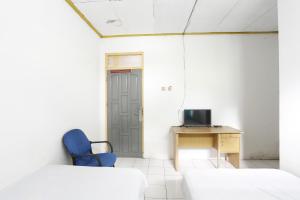 Habitación con silla azul, escritorio y puerta. en SPOT ON 92529 Penginapan Wisma Bintang Syariah, 