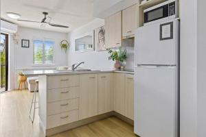 a kitchen with white appliances and a white refrigerator at 1 Bedroom Central Mooloolaba Resort with Pool, Spa, Mini Golf in Mooloolaba
