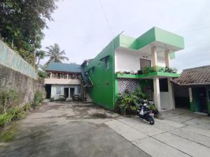 a green and white house with a motorcycle parked in front at SPOT ON 92537 Tetirah Homestay in Salatiga