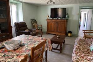 - un salon avec une table à manger et une télévision dans l'établissement Maison de Famille à Soulier, à Gramat