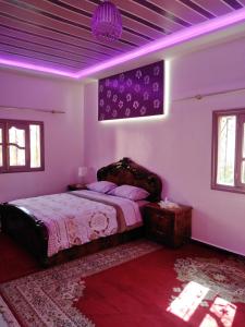 una camera da letto con un grande letto con illuminazione viola di Villa Eden a Ouarzazate