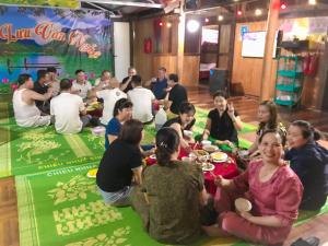 un grupo de personas sentadas alrededor de una mesa comiendo comida en Hoàng Quân Homestay, en Ba Be18