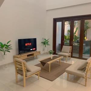 a living room with a flat screen tv and chairs at Namdur Villa Sariwangi - Tropical Villa in Bandung With Private Pool in Bandung