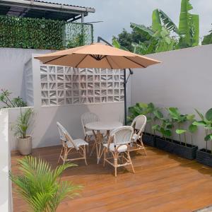 une terrasse avec une table, des chaises et un parasol dans l'établissement Namdur Villa Sariwangi - Tropical Villa in Bandung With Private Pool, à Bandung