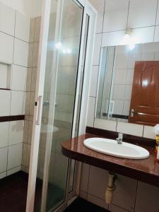 a bathroom with a sink and a glass shower at Lux Suites Hari Apartments Nyali in Mombasa
