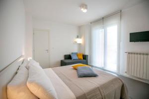 a white bedroom with a bed and a chair at NonSoloMare in Marina di Montemarciano