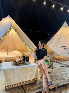 Lang Chai Guesthouse في موي ني: امرأة جالسة على كرسي أمام خيمة