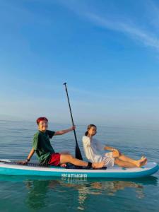 two people sitting on a paddle board in the water at Lang Chai Guesthouse in Mui Ne