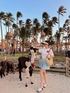 a woman is standing next to a goat at Lang Chai Guesthouse in Mui Ne