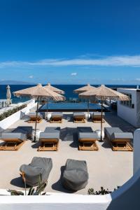 a group of lounge chairs and umbrellas on a beach at Almyra Oia Suites in Oia