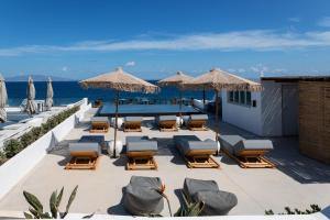 un patio con sillas y sombrillas y el océano en Almyra Oia Suites, en Oia