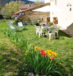 un jardín con mesa, sillas y flores en CASA AL MIGLIO, en Pratolino